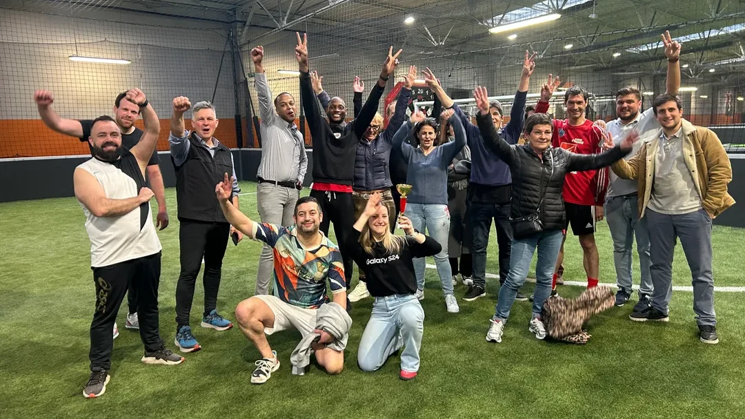 Un groupe célèbre un moment collectif avec des trophées sur un terrain intérieur